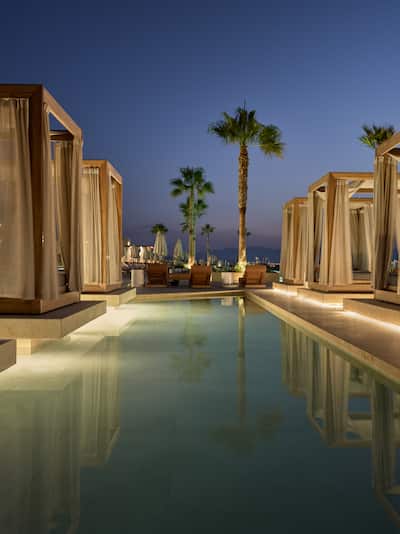 Cabanas in Outdoor Pool Area with Palm Trees at Night