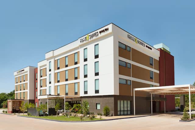Daytime View of Signage on Hotel Exterior, Driveway, Flagpoles, and Landscaping