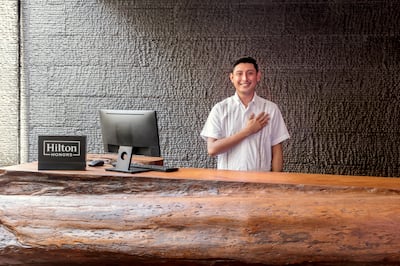 Man with hand over heart standing behind hotel front desk