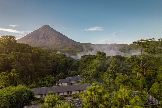 Hotel Exterior with Trees and Green and a Large Mountain in Background