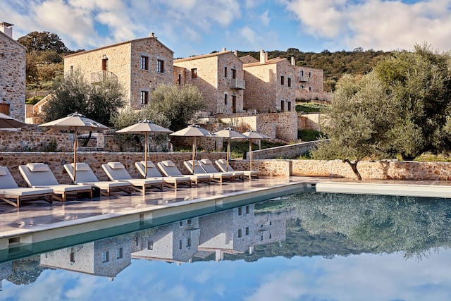 Hotel Exterior and Outdoor Pool Area with Lounge Chairs under Umbrellas
