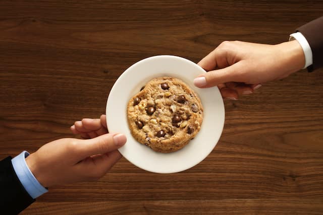Overhead View of Two Hands Holding White Plate With a Cookie