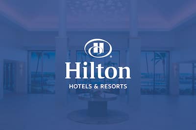 A hotel lobby with the Hilton Hotels & Resorts logo over the top o0f the image