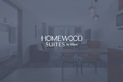 A suite with the Homewood Suites by Hilton logo layered over the image