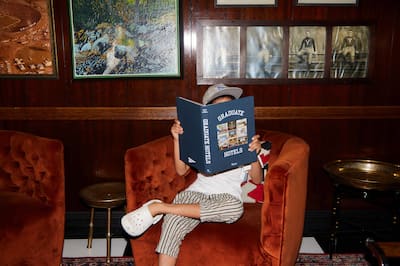 Person reading the Graduate book while sitting on an armchair.