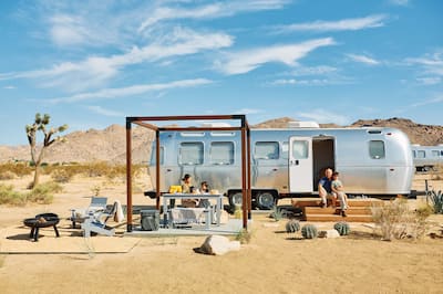family camping outside with mountains in the background