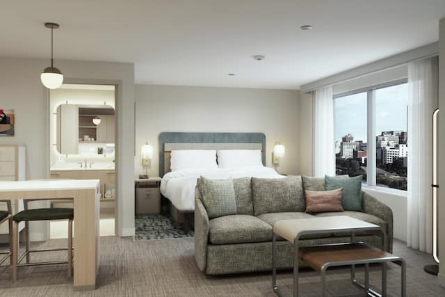 Example rendering of studio suite with bed, sofa, bathroom, and table with two chairs