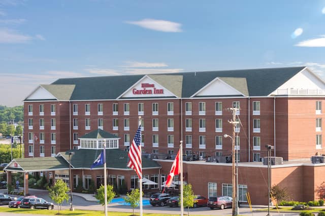 Daytime View of Hotel Exterior, Signage, Flagpole, Landscaping, Circle Drive, and Parking Lot