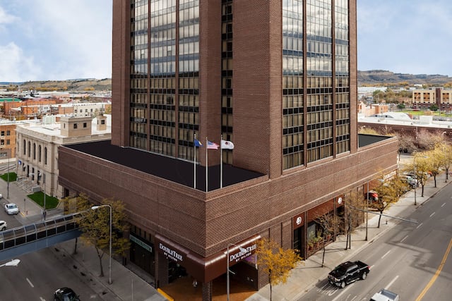 Aerial View of Hotel Exterior. Signage, Flagpoles, Landscaping and Cars on the Street Corner in Daytime