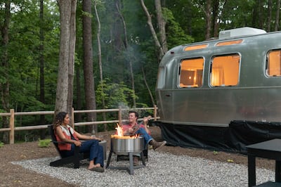 Man and woman sitting around a fire pit in the woods