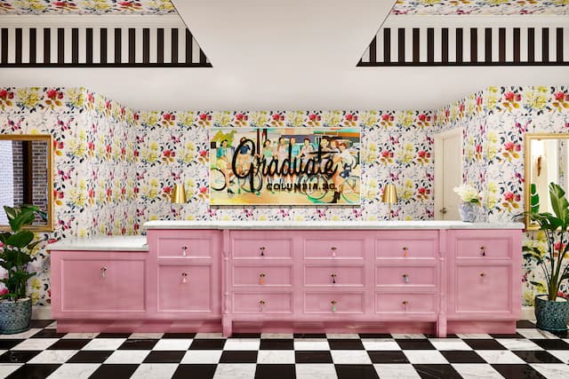 Pink front desk with black and white chequered floor and floral wallpaper