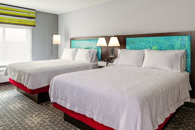 A room at a Hampton hotel with two Queen beds next to each other.