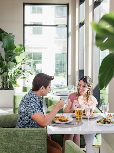 Two women enjoying a meal in a restaurant with green seats and indoor plants
