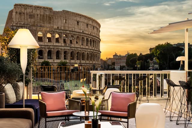 Bar seating area with tables and chairs and view of colosseum