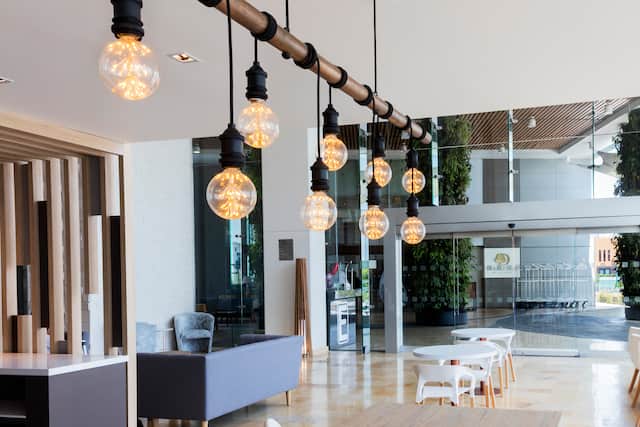 Lobby With Rustic Lighting, Oversize Tables and View of Computers in Business Center