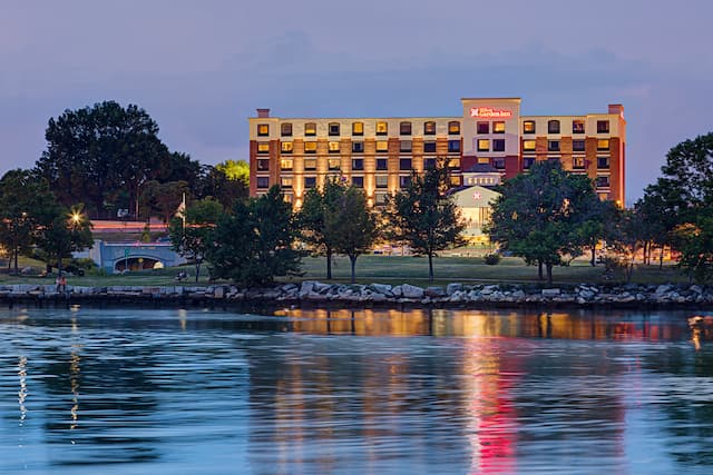 Hotel Exterior With Illuminated Signage, Entrance, and Landscaping at  Night