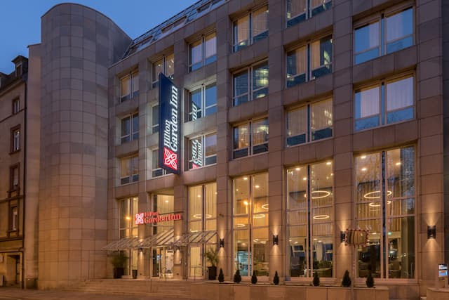 Night time view of modern hotel exterior in pale stone with large windows.