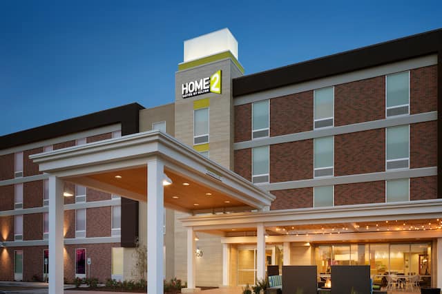 Angled View of Hotel Exterior, Signage, Entrance, and Landscaping Illuminated at Dusk