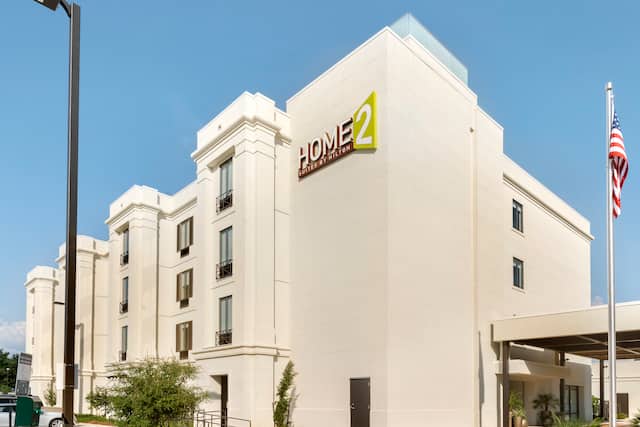 Daytime View of Hotel Exterior, Signage, Flagpole, Landscaping, and Entrance Driveway