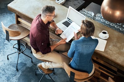 A bird's eye view of a man and a woman sitting at a coffee bar discussing business