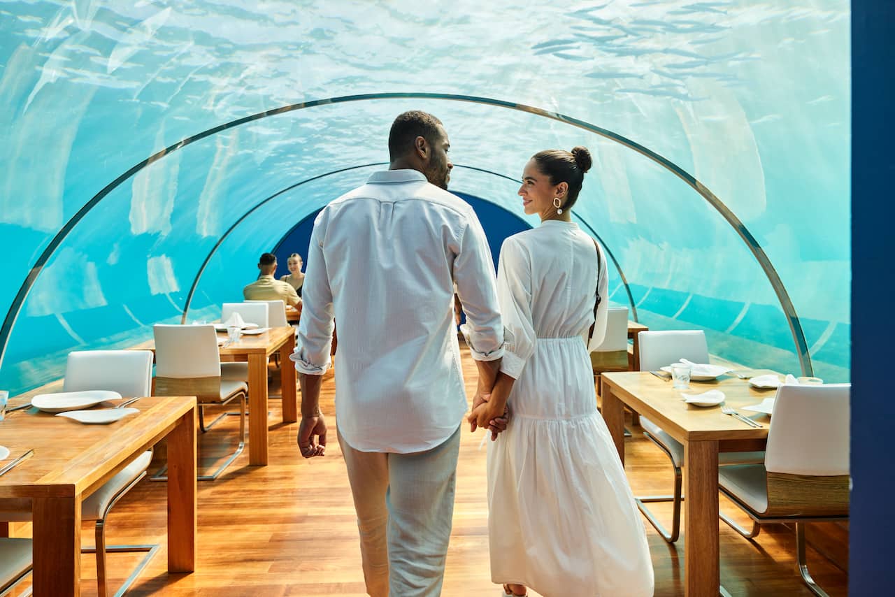 Two people walking into underwater dining
