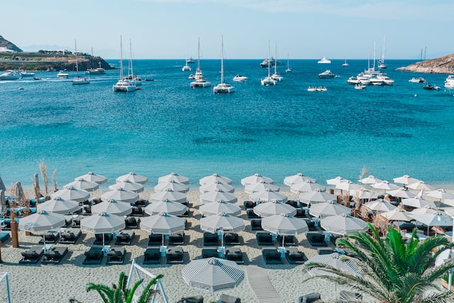 Beach with loungers, parasols and view of boats on the water