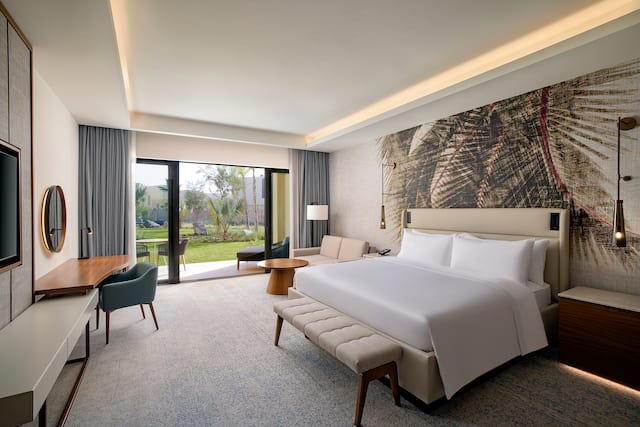 King bedroom with desk, wall mounted TV and outdoor garden area