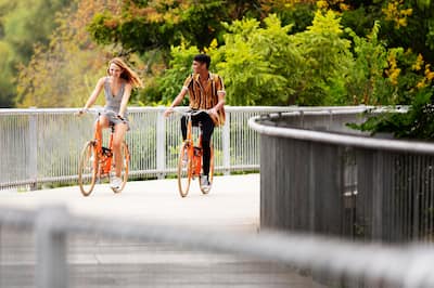 Couple riding orange bikes in park