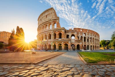 The Colosseum amphitheatre with sunburst and blue sky