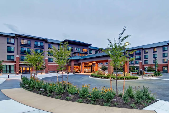Illuminated Hotel Exterior, Porte Cochère, and Landscaping at Dusk Night