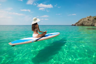 Young woman meditating in a sea on a paddle board in Hawaii.