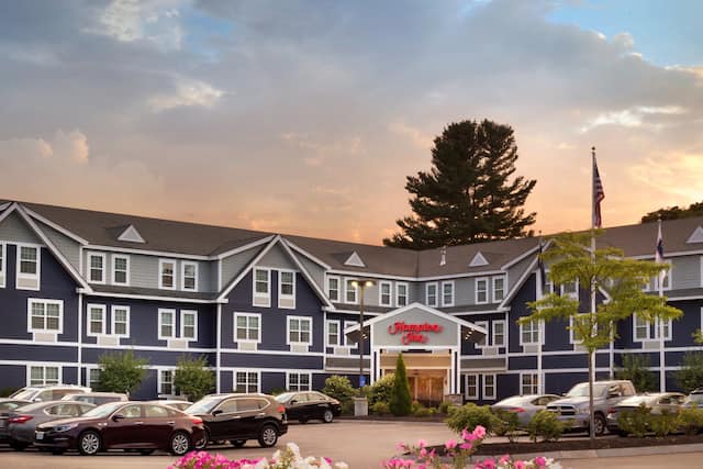 Hotel Exterior, Signage, Circle Drive, Flag Pole and Guest Cars on Parking Lot at Sunset